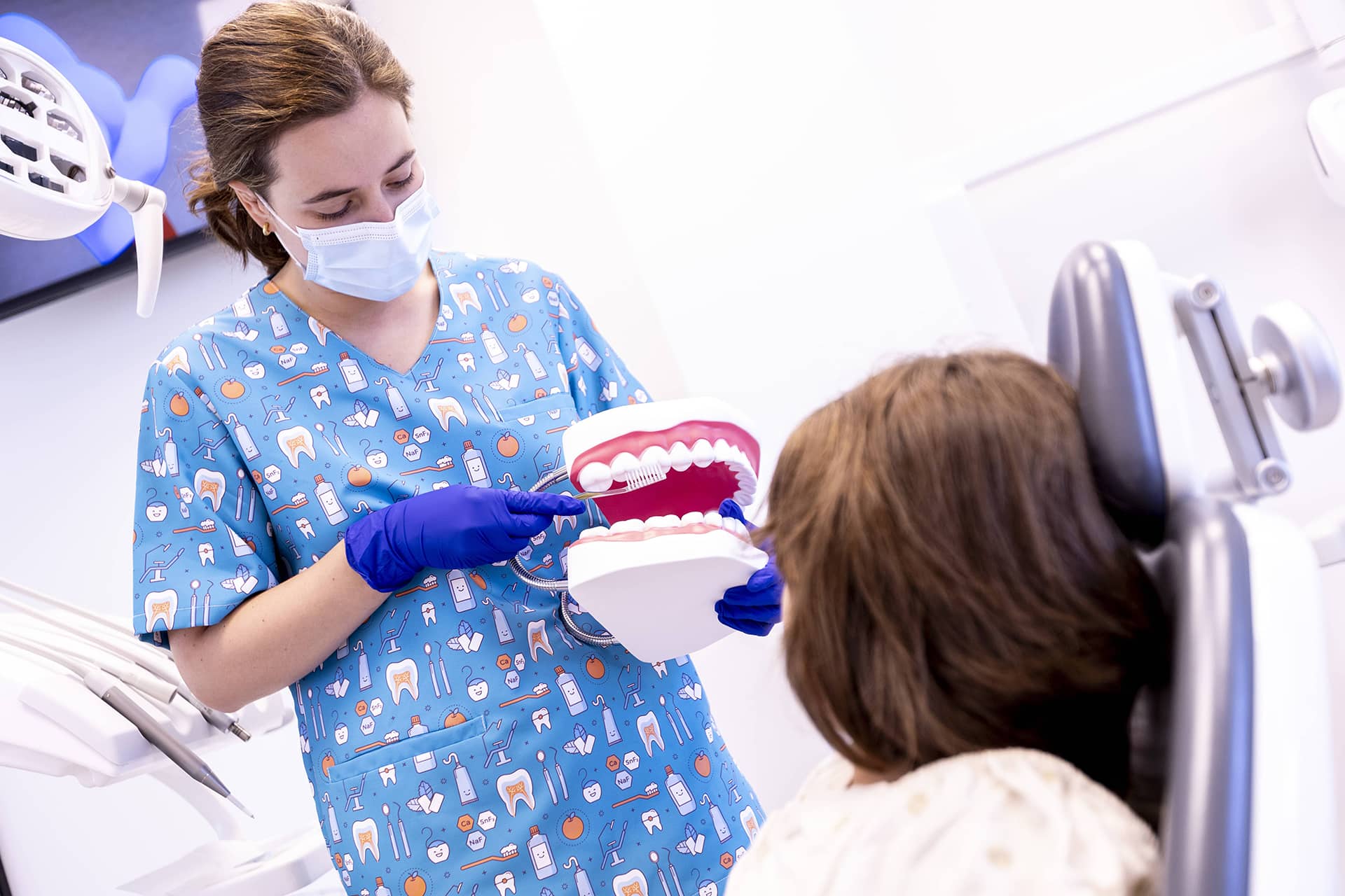 Odontopediatrak hortzetako eskuila batekin  hortzak nola garbitu azaltzen dio haur bati.