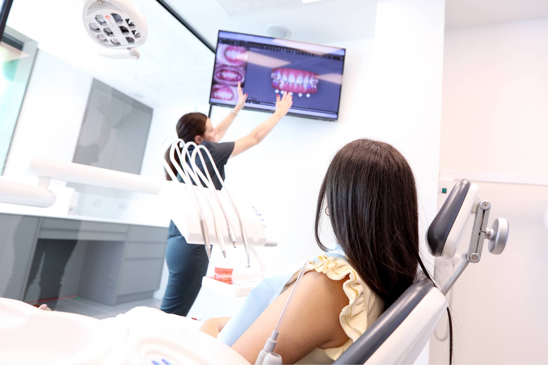 Ortodontzia digitalean aditua den odontologoa hortzetako ortodontzia-tratamendu bat azaltzen ari da paziente bati pantaila batean.